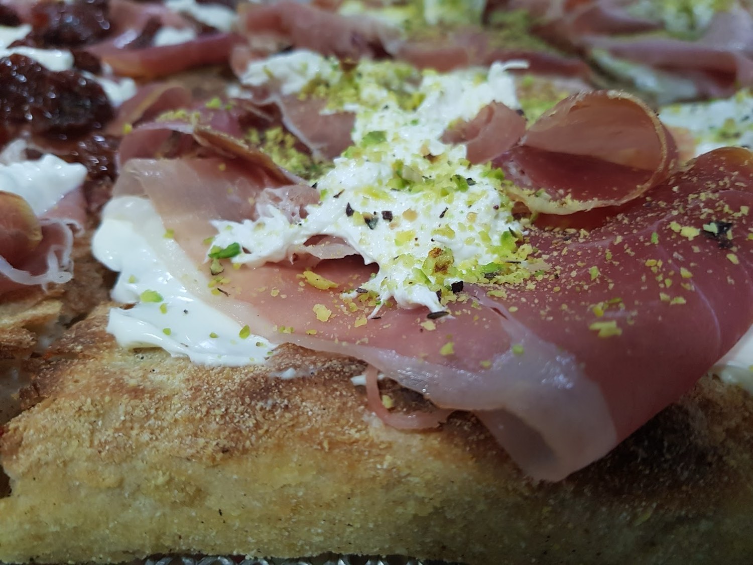 Pizza in pala con crudo, stracciatella e granella di pistacchio
