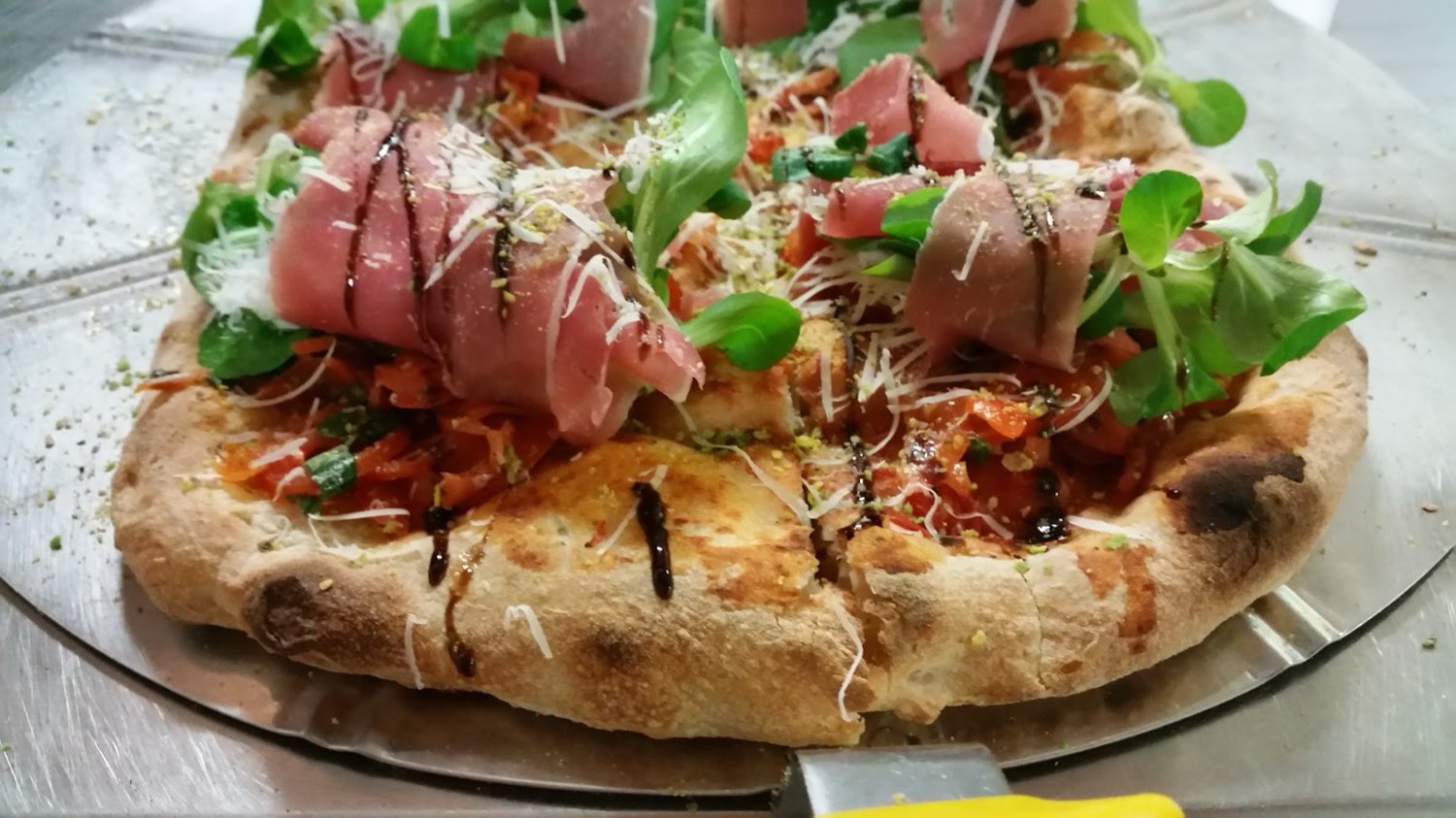 Pizza in pala con crudo, valeriana, pomodorini e granella di pistacchio